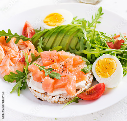 Ketogenic diet breakfast. Salt salmon salad with boiled shrimps, prawns, tomatoes, arugula, eggs and avocado. Keto, paleo lunch.