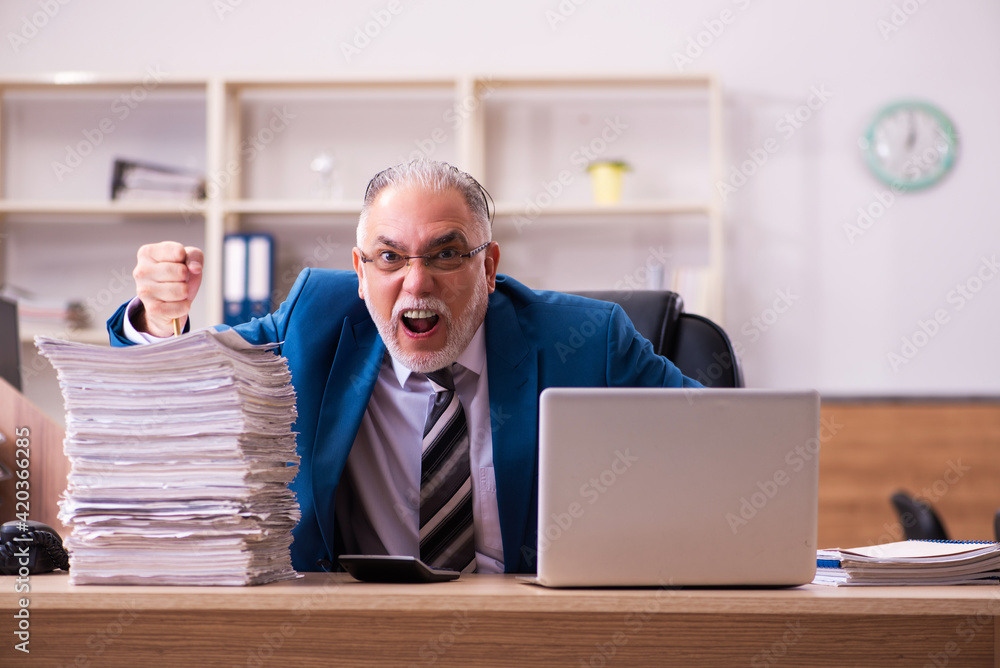 Old male employee unhappy with excessive work in the office Old male employee unhappy with excessive work in the office