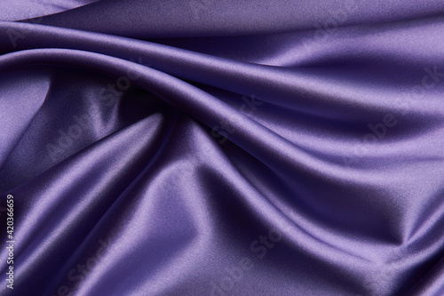 Purple silk fabric background, close-up. Smooth violet satin cloth texture