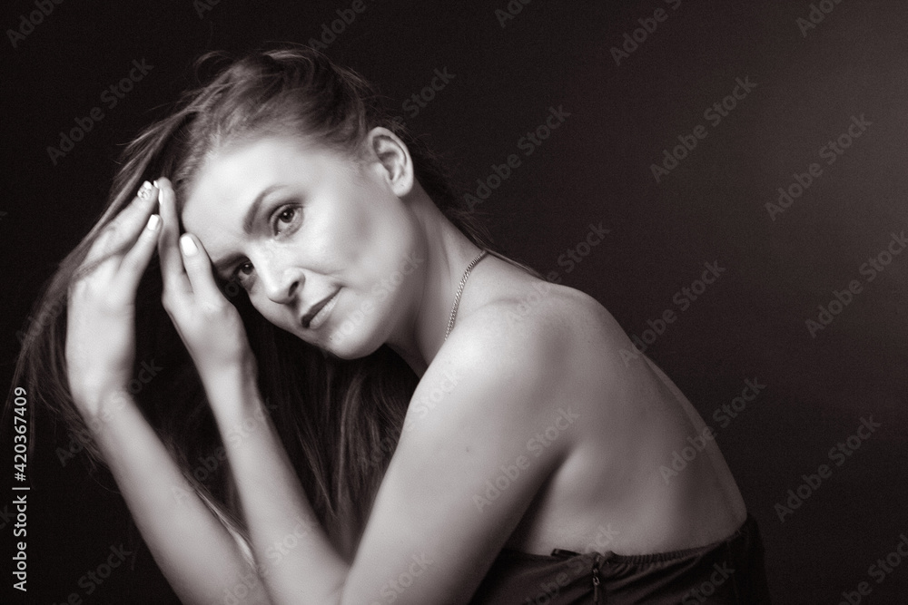 black and white portrait of an adult woman in a studio on a black background. black and white portrait of an adult woman in a studio on a black background.