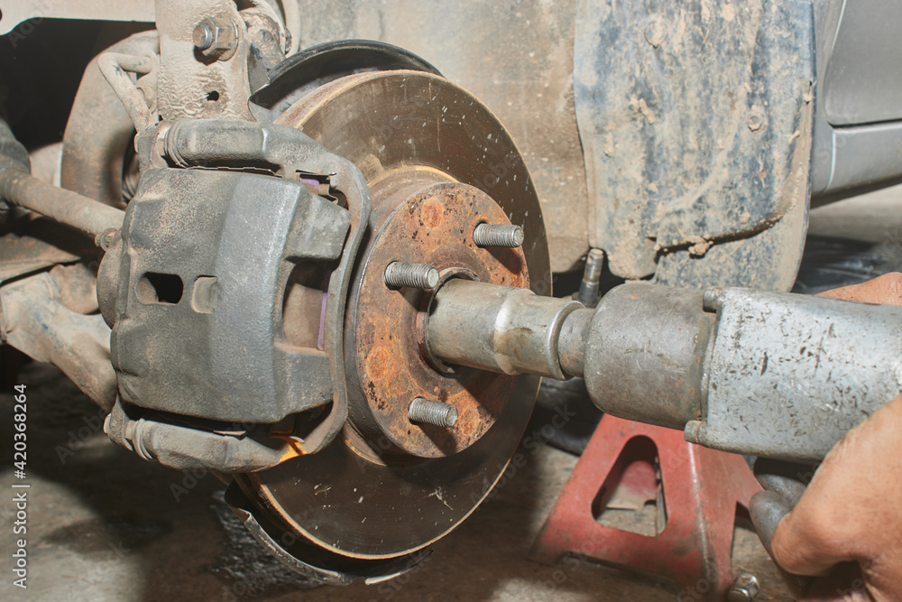 Car Mechanic Using Wind Block Tight Front Drive Shaft Nut in Car Repair Shop Car Mechanic Using Wind Block Tight Front Drive Shaft Nut in Car Repair Shop