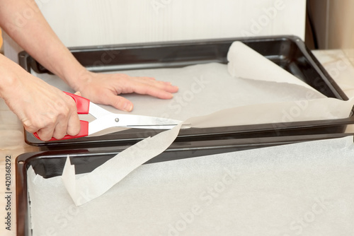 Woman's hands cutting baking paper, detail