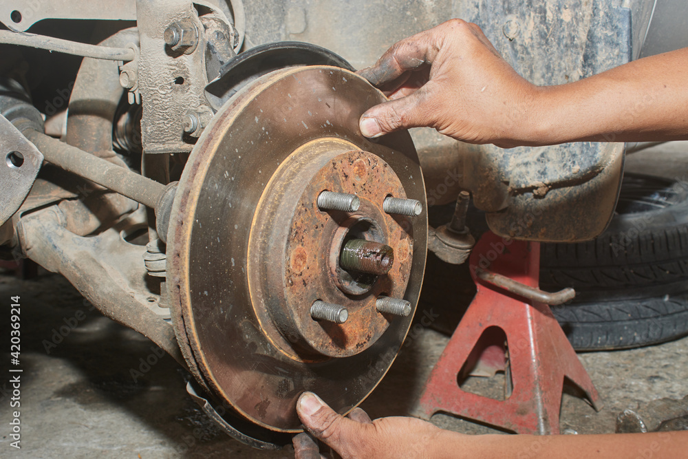 Car Mechanic Assemble Disk Brake to Front Car Wheel Hub in Car Repair Shop Car Mechanic Assemble Disk Brake to Front Car Wheel Hub in Car Repair Shop