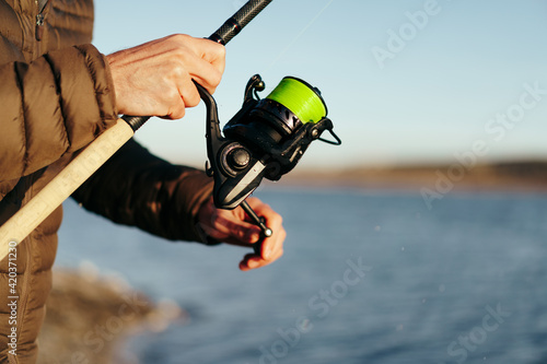 Fisherman hands holding fishing rod close up
