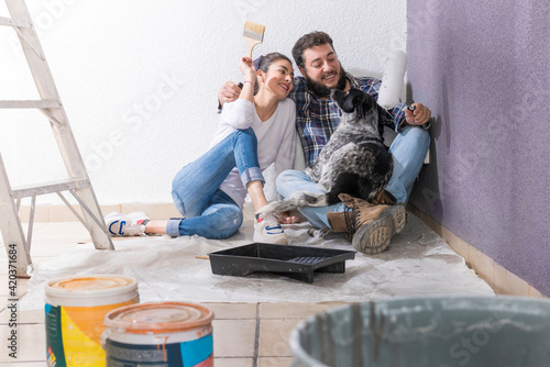Couple opening their new house, young couple painting their new house in the company of their pet, they are happy, one day as a couple opening their house photo
