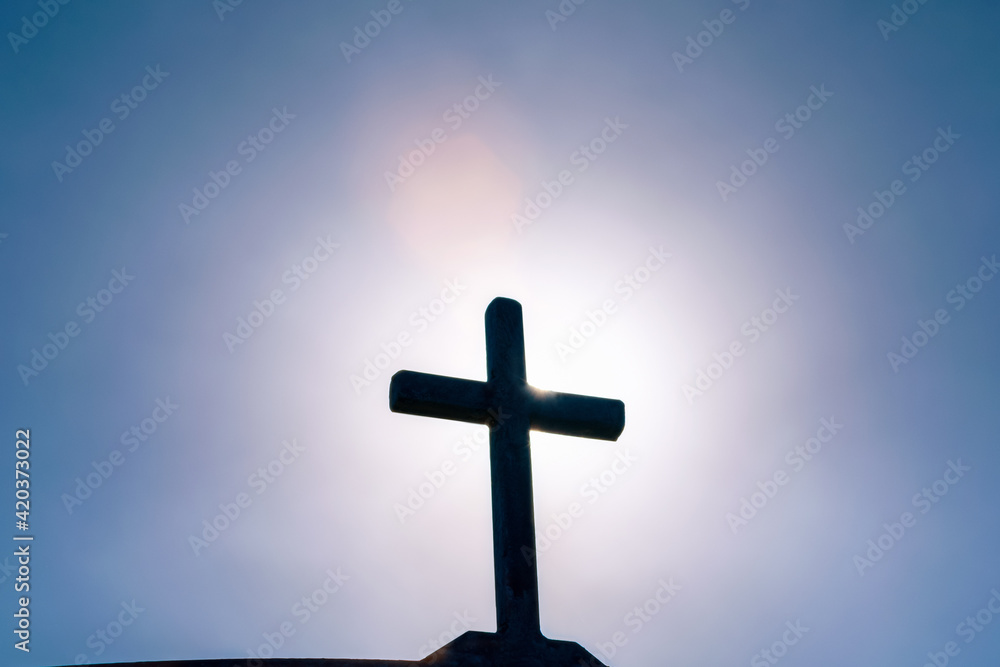 Crucifixion of Jesus Christ, silhouette of an old metal cross, church spire against the background of a dramatic sky with a bright ray of the sun, Ascension day concept, Easter morning Crucifixion of Jesus Christ, silhouette of an old metal cross, church spire against the background of a dramatic sky with a bright ray of the sun, Ascension day concept, Easter morning