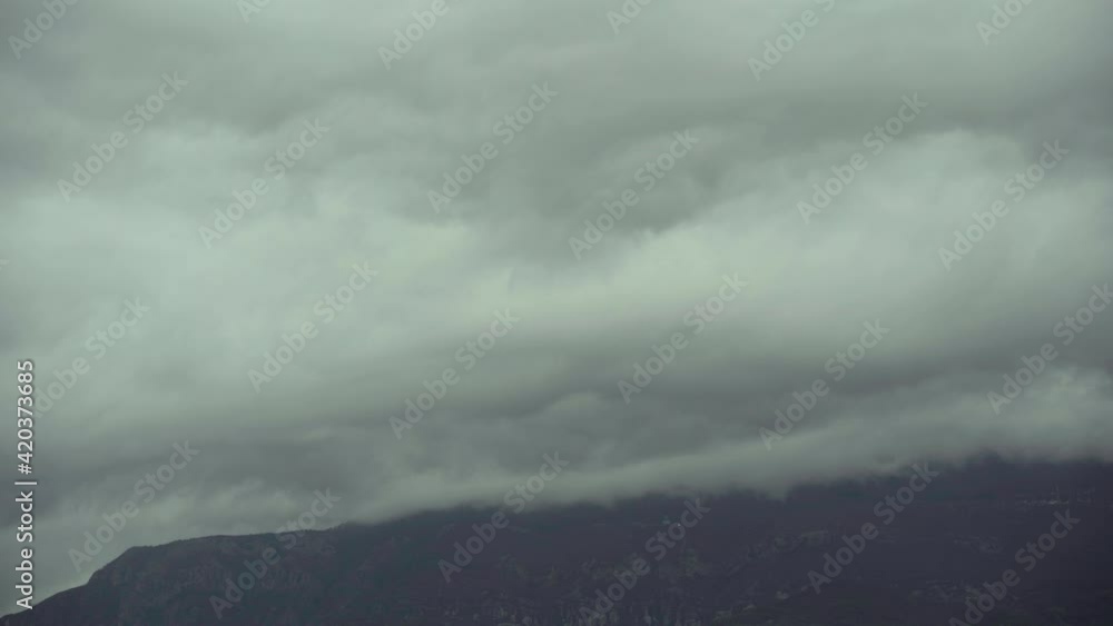 Clouds covering the mountain before rainy storm on a grey landscape in spring