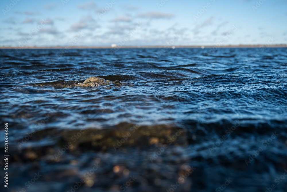 A stone in the water of Lake Liepaja, only its peak can be seen outside, Liepaja, Latvia. A stone in the water of Lake Liepaja, only its peak can be seen outside, Liepaja, Latvia.