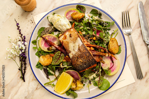 Photography Crispy skin salmon on wilted leaves with creme fraiche