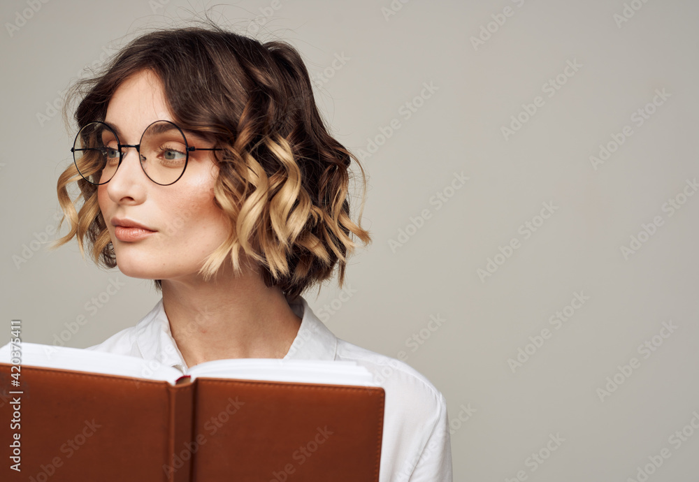 Business woman with open notebook in her hands and glasses on her face, white shirt Business woman with open notebook in her hands and glasses on her face, white shirt
