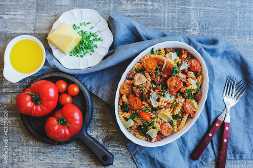 cooking tasty comfort food - italian fusilli pasta baked with meat sauce, cherry tomatoes and cheese