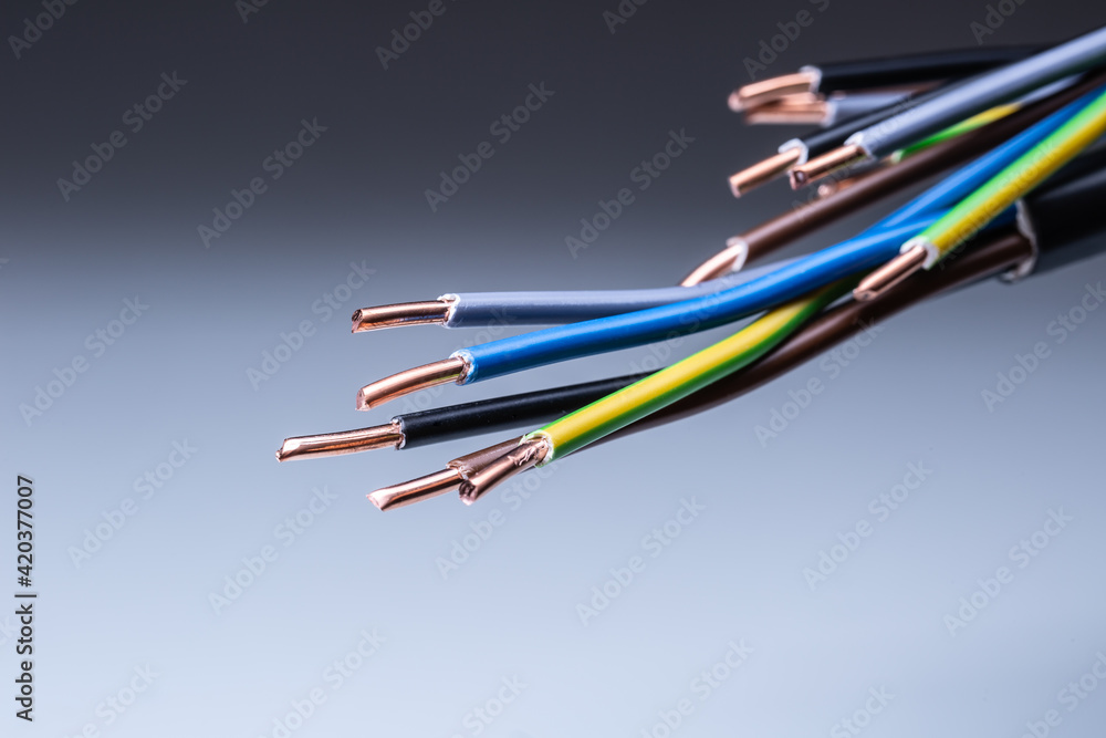 Colorful electrical cables with copper wiring ending on isolated grey background