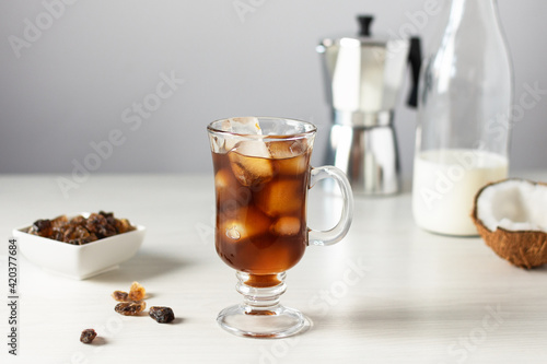 A glass of iced coffee on white wooden table.