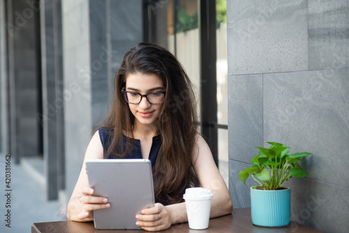Businesswoman with tablet and coffee cup working outdoor. People Lifestyle beauty adult Caucasian woman sitting using tablet video call, one person. 