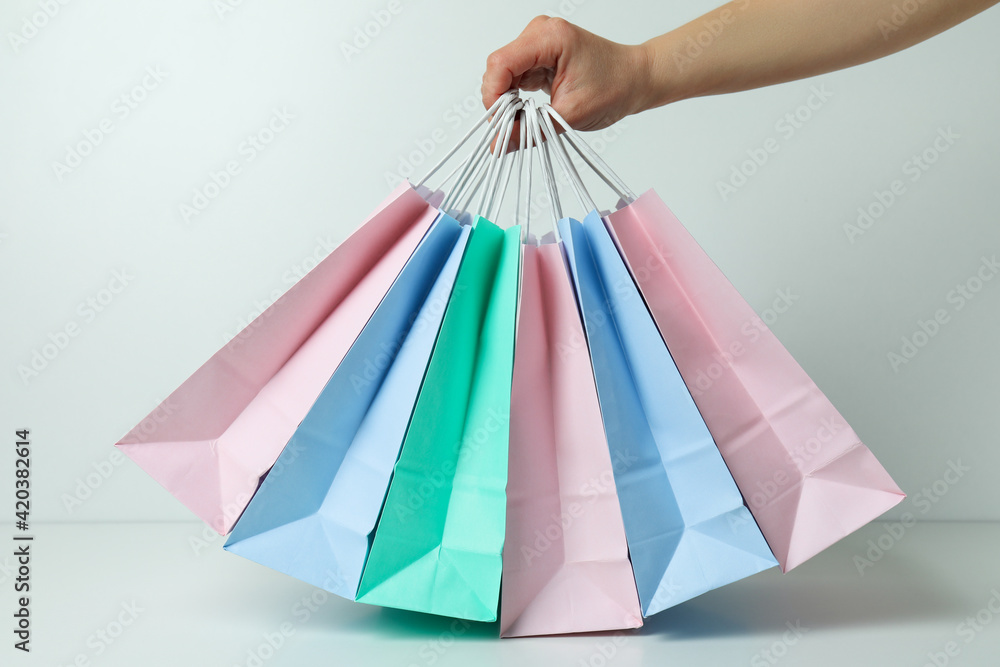 Female hand hold colorful paper bags on white background