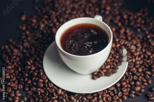 coffee beans and a cup on a white saucer dark background drink