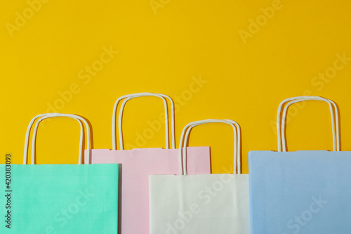 Blank colorful paper bags on yellow background