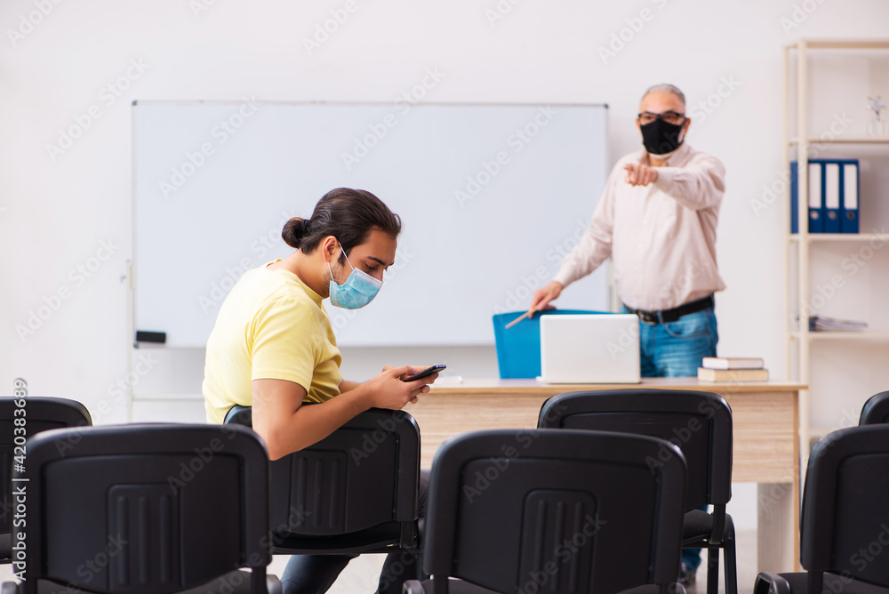 Obraz premium Young male student and experienced teacher in pandemic concept