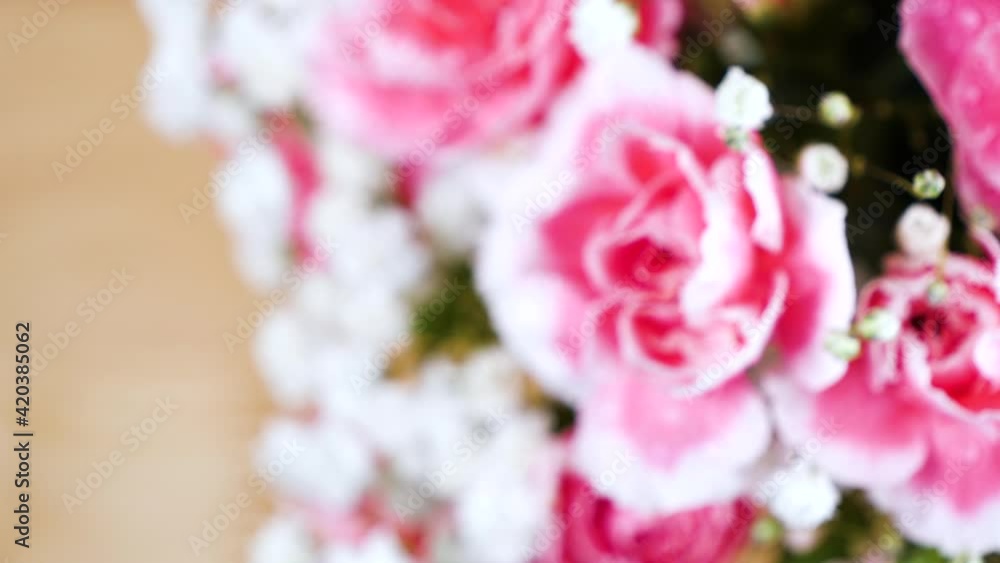 Panning shot of bouquet pink carnation spray flower with water drops on wooden table Panning shot of bouquet pink carnation spray flower with water drops on wooden table