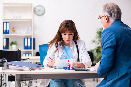 Old businessman visiting young female doctor