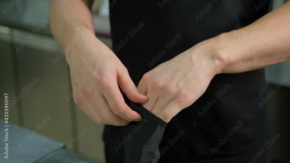 Close-up on a man puts on protective, disposable gloves. New mandatory procedure for customers in restaurant or cafe. New normal, safety concept. Protection against covid-19 Close-up on a man puts on protective, disposable gloves. New mandatory procedure for customers in restaurant or cafe. New normal, safety concept. Protection against covid-19