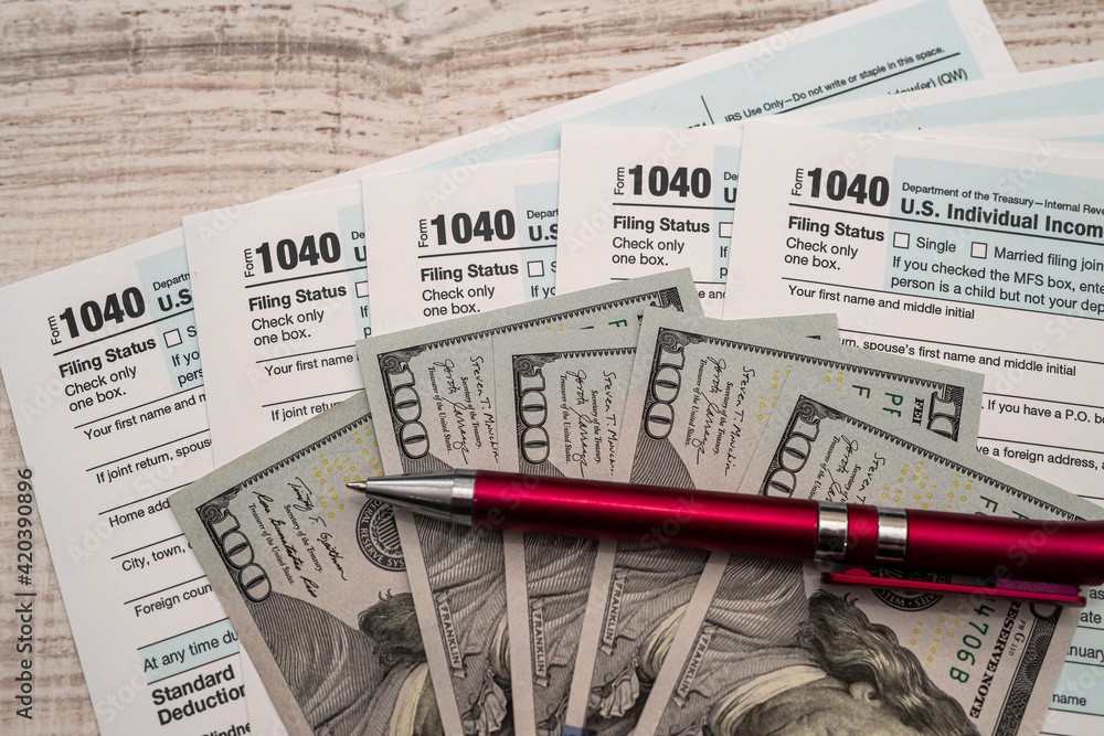 Naklejka premium 1040 US tax form with pen and dollars on desk