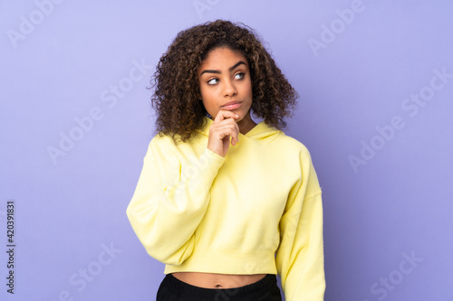 Young African American woman isolated on background having doubts and with confuse face expression