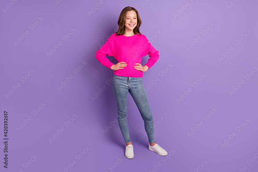 Full size photo of young happy cheerful positive smiling girl wear pink sweater and jeans isolated on violet color background Full size photo of young happy cheerful positive smiling girl wear pink sweater and jeans isolated on violet color background