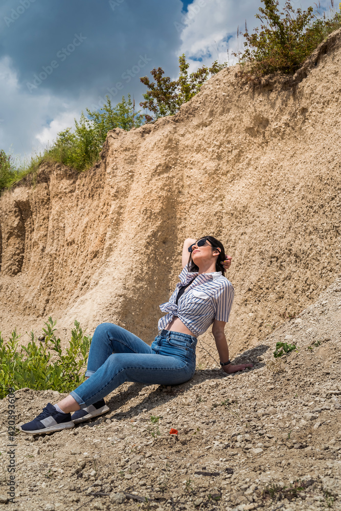 A young beautiful girl in fashionable casual clothes relax in sand quarry