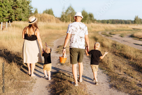 A young family with two children walks in nature outside the city in the summer