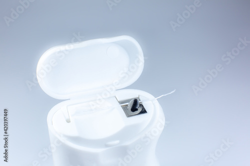 Dental floss on a gray background. Opened box, close up photo.