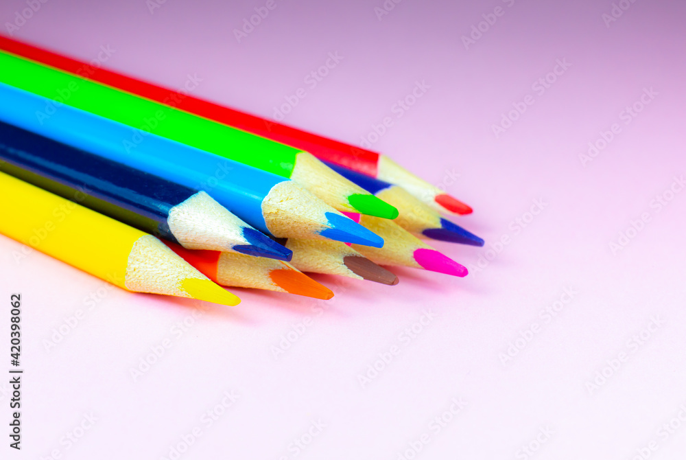 Color pencils lying on pink background. Close up. Back to school concept. Colorful art studying and painting process. Drawing with pencils. Copy space place for postcard wish.