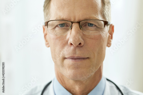 Intelligent man in glasses standing against white background