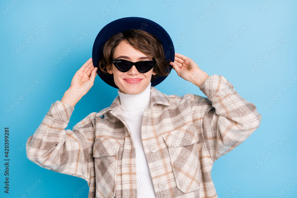 Photo of young attractive girl happy positive smile hands touch retro hat isolated over blue color background Photo of young attractive girl happy positive smile hands touch retro hat isolated over blue color background