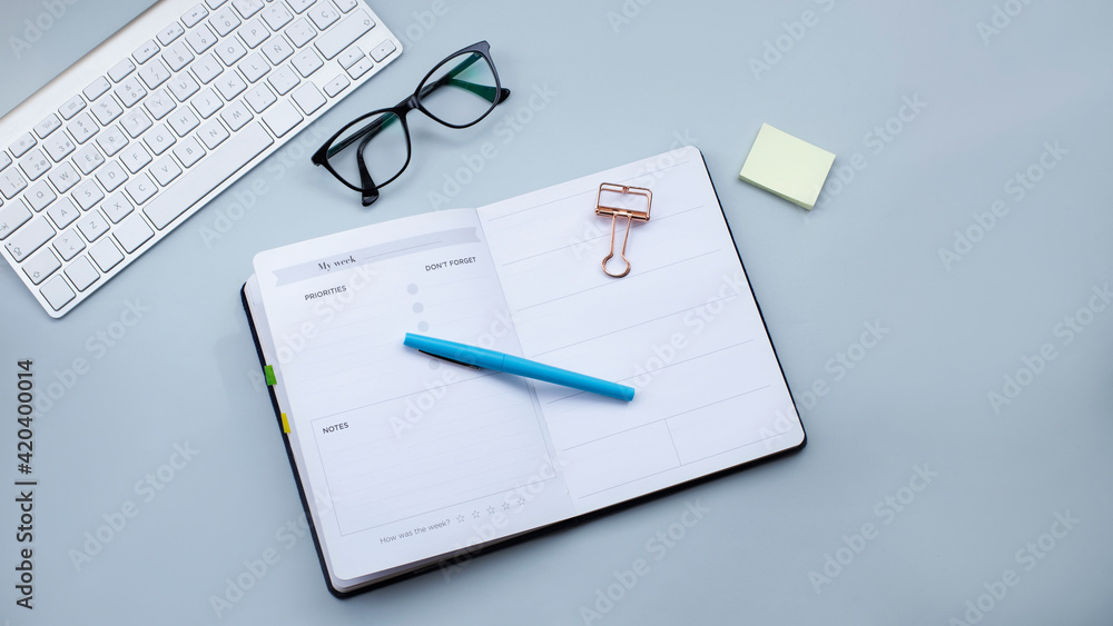 Open planner, keyboard and glasses on light grey background. Small business, taxes, work concept. Web banner image Open planner, keyboard and glasses on light grey background. Small business, taxes, work concept. Web banner image
