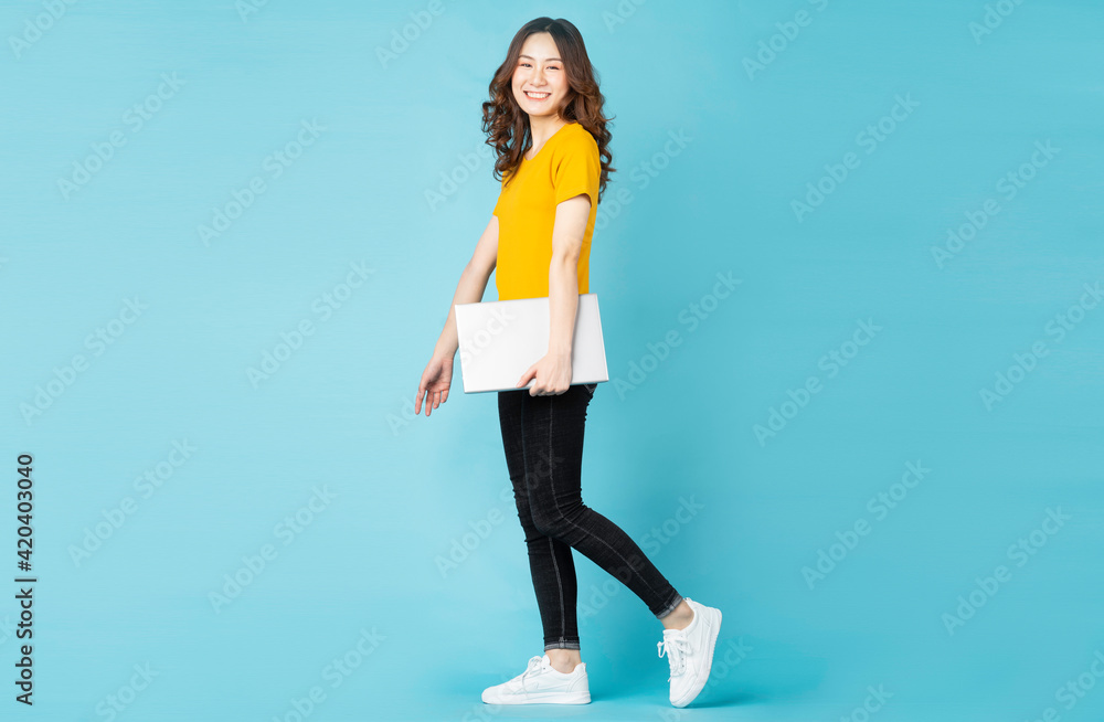 Young Asian girl holding laptop and walking on background Young Asian girl holding laptop and walking on background