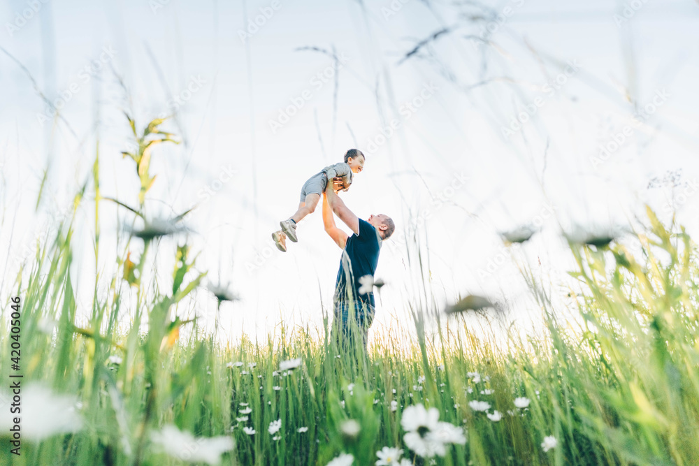 Smiling father holding adorable little son in arms on sunny day. Smiling father holding adorable little son in arms on sunny day.