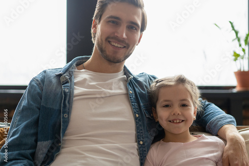 Portrait of handsome father and his cute daughter hugging and smiling.
