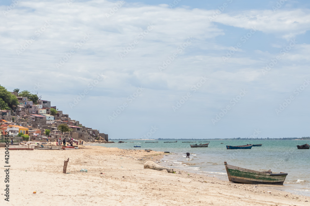 Beach view with fishermen and traditional Angolan boats, in Luanda beach, ghetto as background