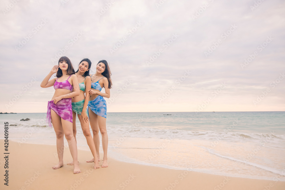 Three young women friends happily wear this bikini on a beach in Nai Thon Beach, Phuket Province, Thailand. Portrait of happy young woman smiling at sea. Concept about Travel, happiness, nature