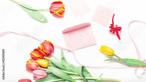 Fototapeta Naklejka Na Ścianę i Meble -  View from above tulips and gift box with copy space on white. Background for womens day, 8 March Valentines day, 14 February. Flat lay style, top view, mockup, template, overhead. Greeting card