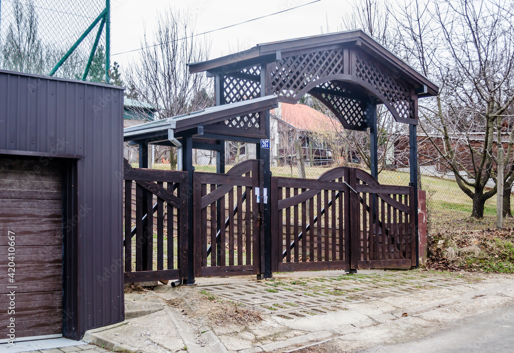 Closed, slatted, black wooden gate of private property. 