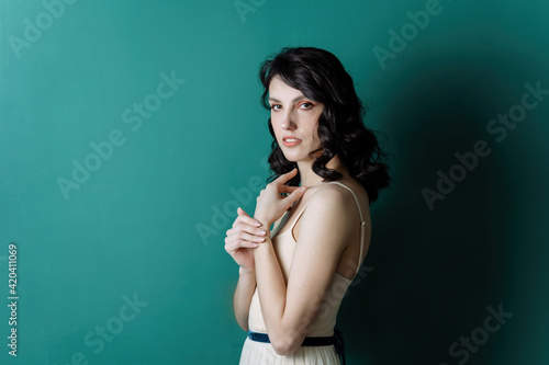 Elegant lady portrait.Pearls jewelry set posing isolated on studio green background. Stands with his shoulder to the camera. © Alex Li