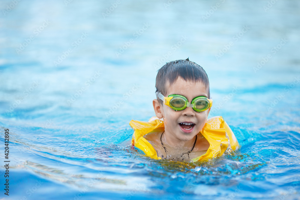 smiling little boy swims in the pool