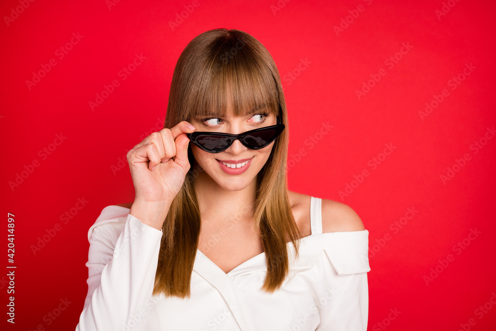 Photo of young woman happy positive smile hand touch glasses look empty space isolated over red color background Photo of young woman happy positive smile hand touch glasses look empty space isolated over red color background