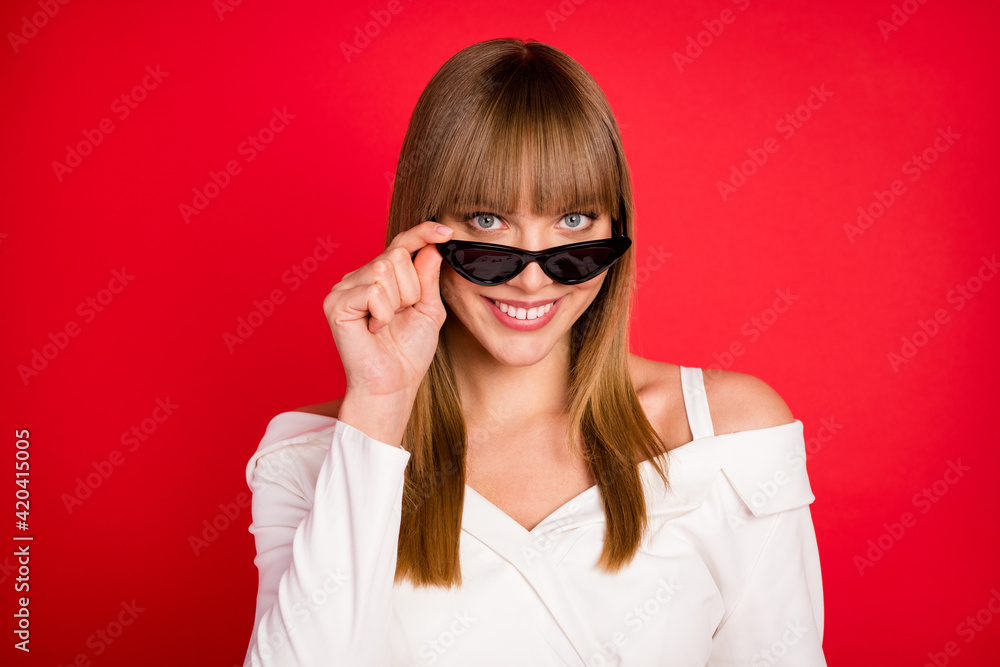 Photo of young attractive woman happy positive smile hand touch sunglass isolated over red color background