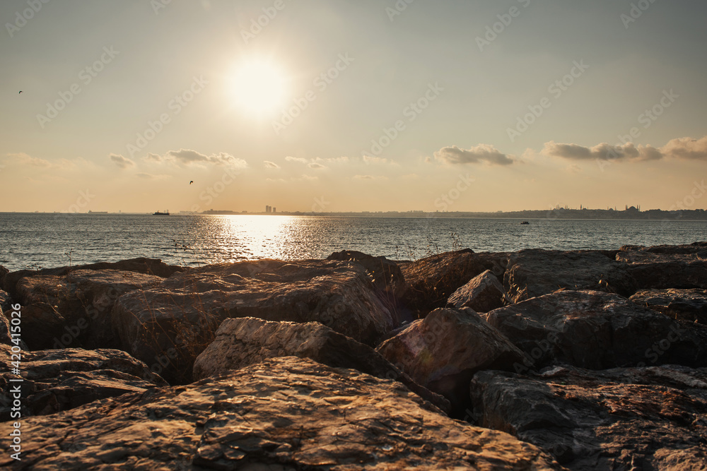 Scenic view of stones on coast of sea during sunset