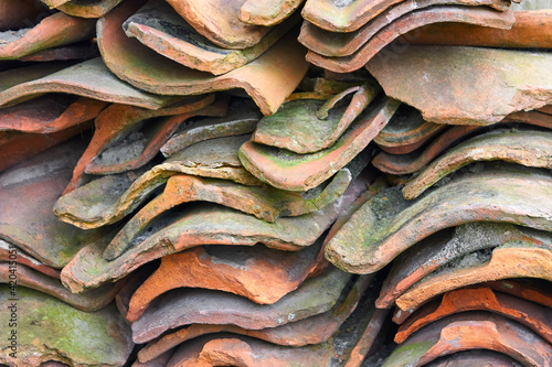 A stack of old orange roof tiles with green algae.