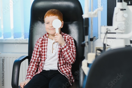 Child at eye sight test. Little kid selecting glasses at optician store. Eyesight measurement for school kids. Eye wear for children. Doctor performing eye check. Boy with spectacles at letter chart.