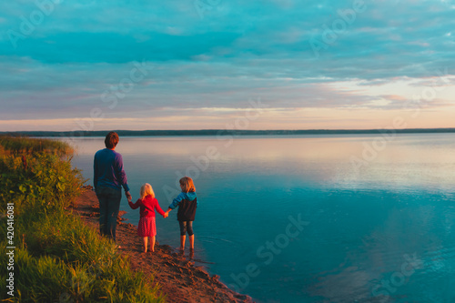 father with kids on beach at sunset, family vacation in nature
